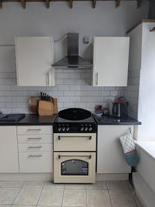 a kitchen with a stove and white cabinets at The Stables in Aglish +6 photos