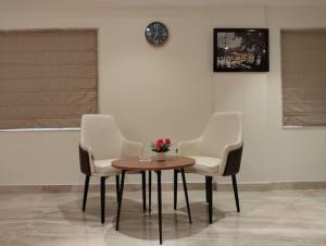 three chairs and a table and a clock on a wall at Eennra Ssubarna in Baharampur