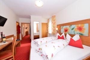Schlafzimmer mit einem weißen Bett und roten Kissen in der Unterkunft Hotel Marienhof in Bad Wörishofen