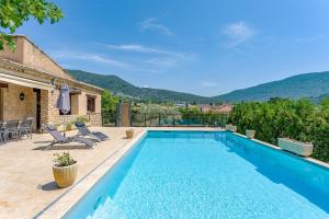 a swimming pool with chairs and a house at La Villa D'antan - Piscine in Nyons