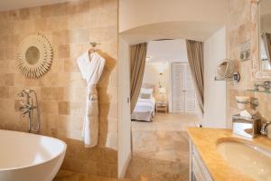 a bathroom with a tub and a sink and a bed at La Bastide des Salins in Saint-Tropez