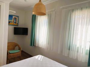 a bedroom with a bed and a television and a window at Felicitta Stay & Joy in Seferihisar