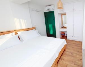 a bedroom with a large white bed and a green door at Felicitta Stay & Joy in Seferihisar