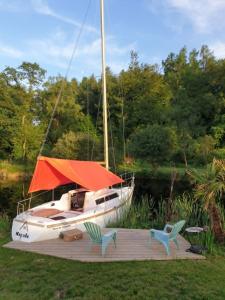 a boat sitting on a dock with two chairs at Bateau Gîte in Berné