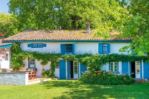 a blue and white house with flowers in the yard at Maison De Charme Avec Jacuzzi in Arcangues