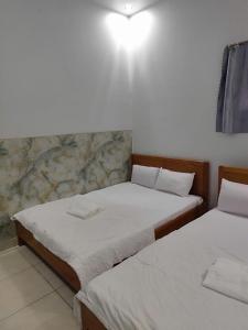 two twin beds in a room with a wall at Khách Sạn Lâm Tiên - Lam Tien Hotel in Bùi Tiếng