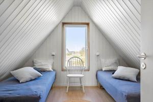 two beds in a room with a window and a chair at 1335-Vestervig-Spovevej-11 in Vestervig