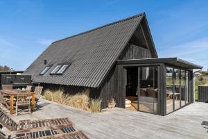 a black roofed house with a wooden deck at 1335-Vestervig-Spovevej-11 in Vestervig
