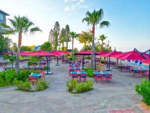 a patio with tables and chairs and red umbrellas at Senza Sunset Beach Hotel in Alanya