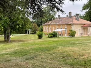 a large brick house with a grass yard at La Belle Chartreuse in Manciet