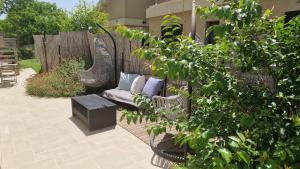 a patio with a couch with pillows and a fence at The corner in Sde Ilan in Sede Ilan
