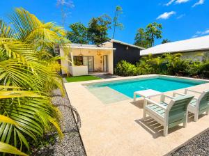 a swimming pool with a table and chairs next to a house at Lalola de Puerto in Puerto Viejo
