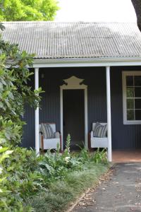 une maison bleue avec 2 chaises sur la terrasse couverte dans l'établissement Mill Cottages, à Lidgetton