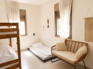 a bedroom with a bed and a chair and windows at The corner in Sde Ilan in Sede Ilan