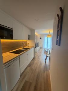 a kitchen with white cabinets and a wooden floor at Apartamentos Leyre Candanchú in Candanchú +50 photos