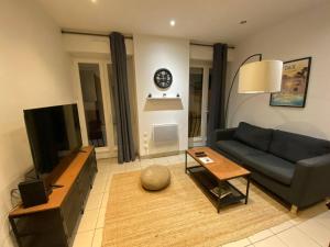 a living room with a couch and a clock on the wall at Dax Fontaine Chaude Center in Dax