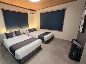 two beds in a hotel room with two large windows at KUON Onomichi - クオン尾道 in Onomichi +28 photos