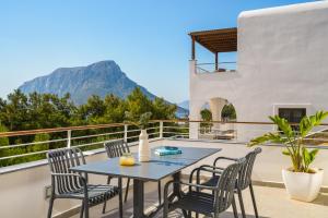 a table and chairs on a balcony with a mountain in the background at Galma Luxury Homes in Kalymnos