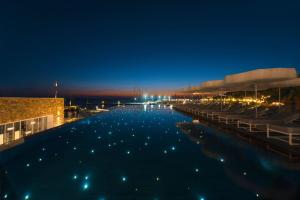 a large swimming pool with a dock at night at Mykonos Riviera Hotel & Spa, a member of Small Luxury Hotels of the World in Tourlos