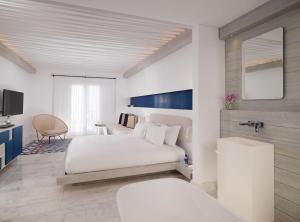 a hotel room with a bed and a desk at Mykonos Riviera Hotel & Spa, a member of Small Luxury Hotels of the World in Tourlos +30 photos