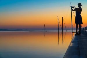 a woman standing on a dock holding a pole at Mykonos Riviera Hotel & Spa, a member of Small Luxury Hotels of the World in Tourlos