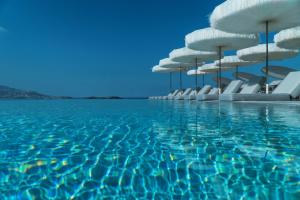 a pool with white chairs and blue water at Mykonos Riviera Hotel & Spa, a member of Small Luxury Hotels of the World in Tourlos