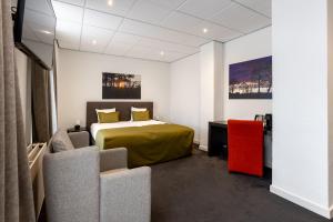 a bedroom with a bed and two chairs in a room at De Zwaan Delden in Delden
