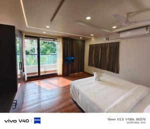 a bedroom with a white bed and a large window at Velmora Luxe Residences in Madurai