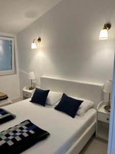 a bedroom with a white bed with blue pillows at Apartments Peace&Love in Baška