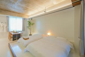 a white bedroom with two beds and a table at 스테이머묾 m2 in Jeonju