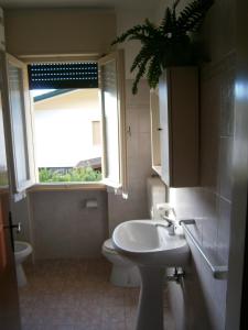 bagno con lavandino, servizi igienici e finestra di Luca a Bibione