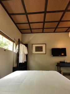 a bedroom with a white bed and a tv at Lavung Village in Ða Gia +79 photos