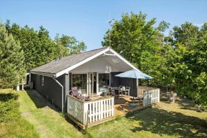 a black cottage with a deck and an umbrella at OH293-Hadsund-Jaegerskoven-15 in Hadsund +15 photos