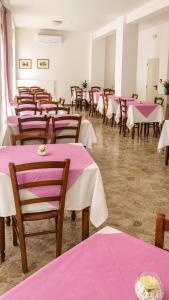 a room filled with tables and chairs with pink tablecloths at Hotel Le Ali in Rimini +13 photos