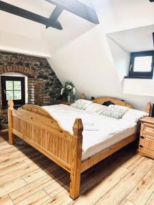 a wooden bed in a room with a brick wall at Apartmány Haberschie in Řehlovice
