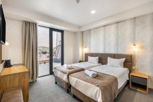 a hotel room with two beds and a balcony at Brooch Boutique Hotel in Tbilisi City