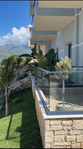 ein Haus mit Glaszaun und einem Garten mit Bäumen in der Unterkunft Bay View Hotel in Himarë