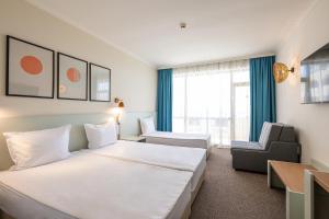 a hotel room with two beds and a chair at SOL by Meliá Nessebar Mare All Inclusive in Nesebar +82 photos