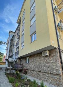 an apartment building with a brick wall next to a building at Apartman Lambros 2 in Soko Banja