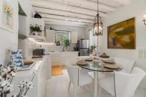 a white kitchen with a table and white chairs at Nest Gateway - Panoramic Mountain Views in Apoíkia
