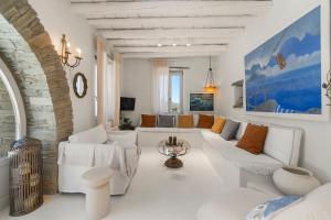 a white living room with a white couch and chairs at Nest Gateway - Panoramic Mountain Views in Apoíkia