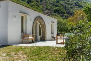 a white house with a table and chairs on a patio at Nest Gateway - Panoramic Mountain Views in Apoíkia