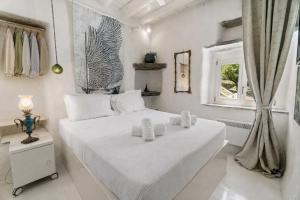 a white bedroom with a bed with towels on it at Nest Gateway - Panoramic Mountain Views in Apoíkia