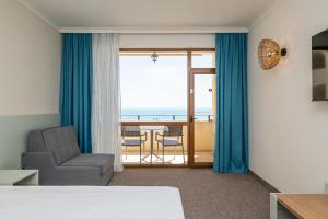 a room with a bed and a chair and a balcony at SOL by Meliá Nessebar Mare All Inclusive in Nesebar