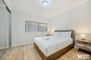 a white bedroom with a bed and a window at KozyGuru | Penrith | Spacious Ground Floor Gem in Penrith