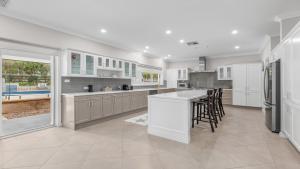 a large kitchen with white cabinets and a large island at Vintage Lodge in Pokolbin +11 photos