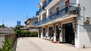 a building with a balcony and tables and chairs at Hotel Le Ali in Rimini