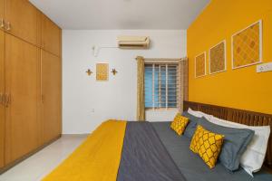 a bedroom with a bed and a yellow wall at Vintage Haven Leafy Getaway Luxury Villa in Indiranagar by Spacez in Bangalore