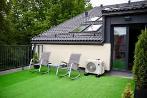 a patio with two chairs and a heater on the grass at Bohemia Jacuzzi & Sauna Apartment in Klaipėda
