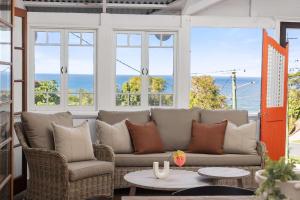 a living room with a couch and chairs and the ocean at Pacific Terrace Beach House in Coolum Beach